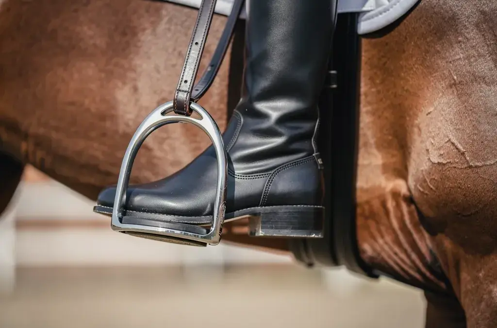 Mann reitet im Sattel und stellt Steigbügel richtig für optimalen Halt ein